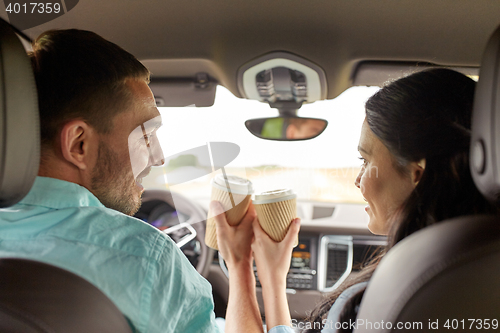 Image of happy man and woman driving in car with coffee