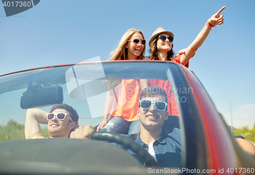 Image of happy friends driving in cabriolet car at country