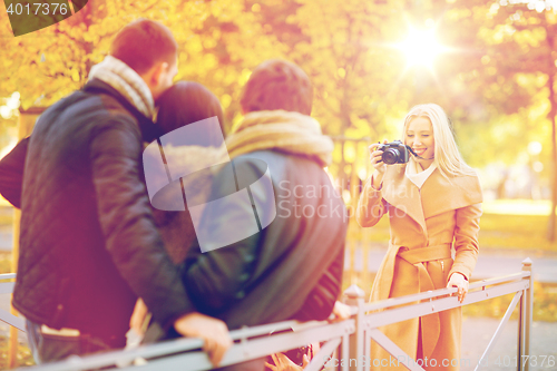 Image of group of friends with photo camera in autumn park