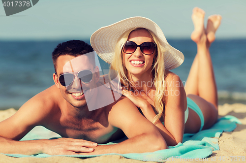 Image of happy couple in swimwear lying on summer beach