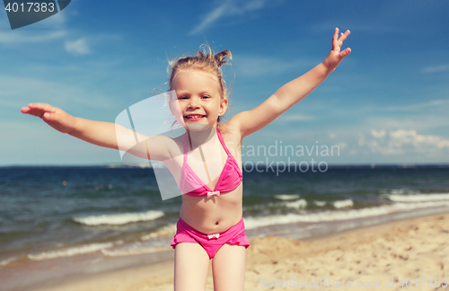 Image of happy little girl in swimwear having fun on beach