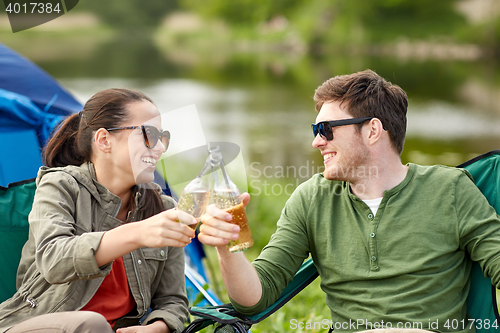 Image of happy couple clinking drinks at campsite tent