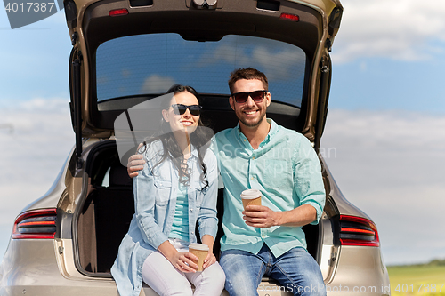 Image of happy couple with coffee at hatchback car trunk