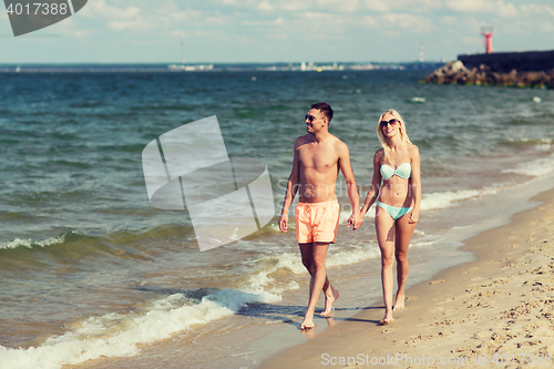 Image of happy couple in swimwear walking on summer beach