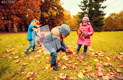 Image of group of children collecting leaves in autumn park