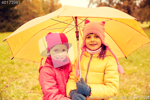 Image of happy little girls with umbrella in autumn park