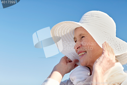 Image of happy senior woman in sun hat on summer beach