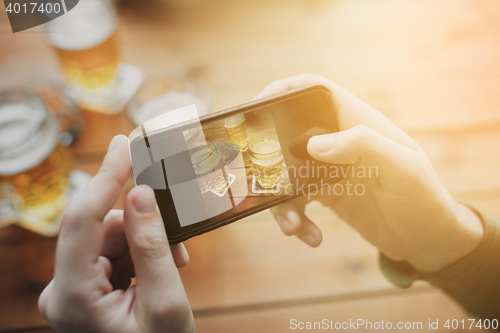 Image of close up of hands with smartphone picturing beer