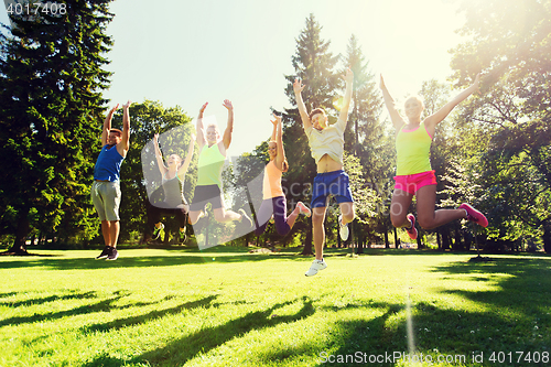 Image of group of happy friends jumping high outdoors