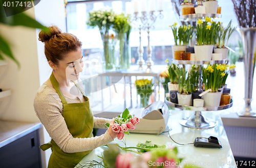 Image of smiling florist woman making bunch at flower shop