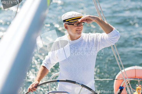 Image of senior man at helm on boat or yacht sailing in sea