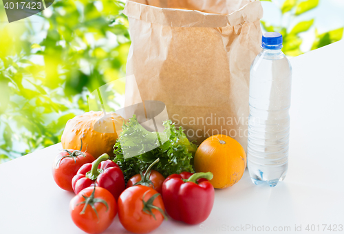 Image of close up of paper bag with vegetables and water