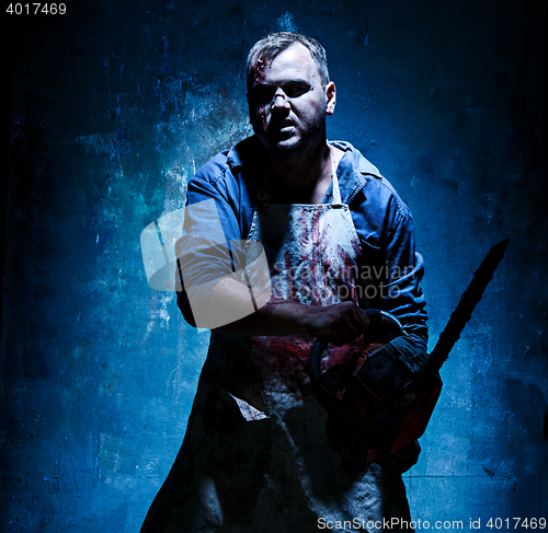 Image of Bloody Halloween theme: crazy killer as butcher with electric saw