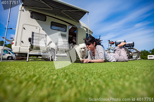 Image of Woman on the grass with a dog looking at a laptop