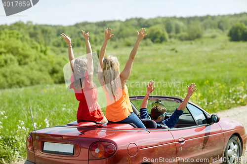 Image of happy friends driving in cabriolet car at country