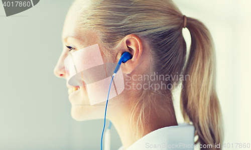 Image of close up of happy woman in earphones at home