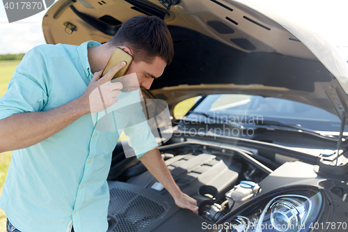 Image of man with broken car calling on smartphone