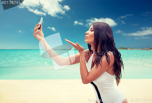 Image of young woman taking selfie with smartphone