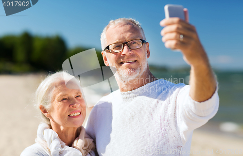 Image of happy senior couple hugging on summer beach