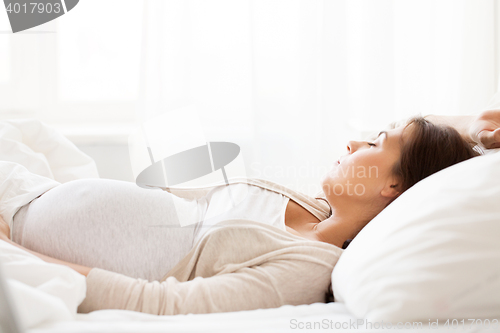Image of happy pregnant woman sleeping in bed at home