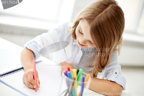 Image of happy girl drawing with felt-tip pen in notebook