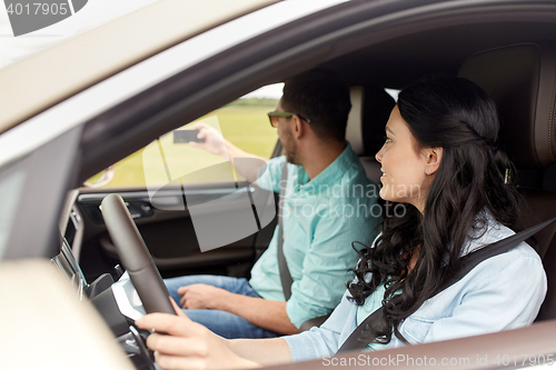 Image of happy couple in car taking selfie with smartphone