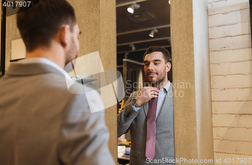 Image of man trying tie on at mirror in clothing store