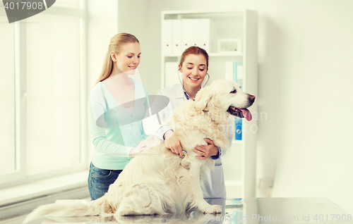 Image of happy woman with dog and doctor at vet clinic