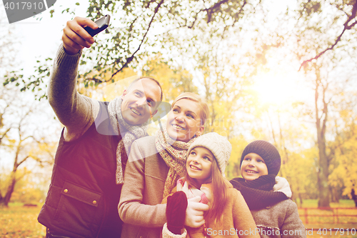 Image of happy family with camera in autumn park