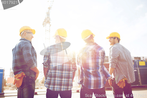 Image of group of smiling builders in hardhats outdoors