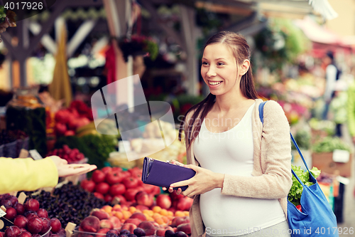 Image of pregnant woman with wallet buying food at market