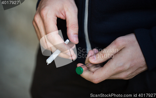Image of close up of addict hands with marijuana joint tube