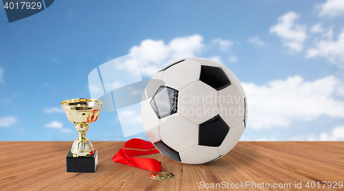 Image of close up of football ball, golden cup and medal