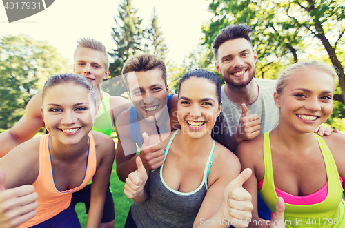 Image of group of happy sporty friends showing thumbs up
