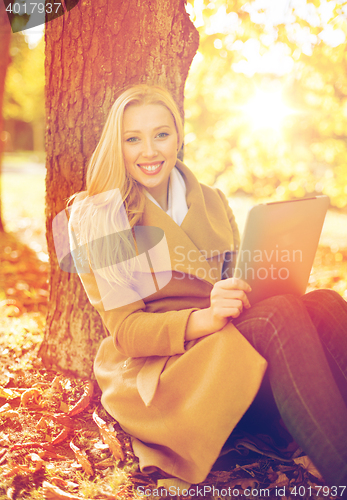 Image of woman with tablet pc in autumn park