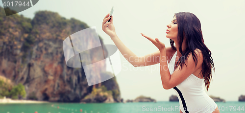 Image of young woman taking selfie with smartphone