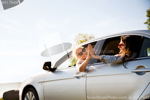 Image of happy teenage girls or women in car at seaside