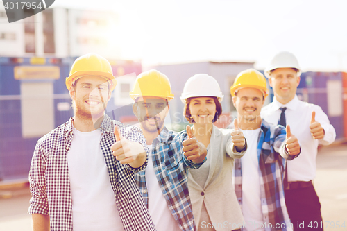 Image of group of smiling builders in hardhats outdoors