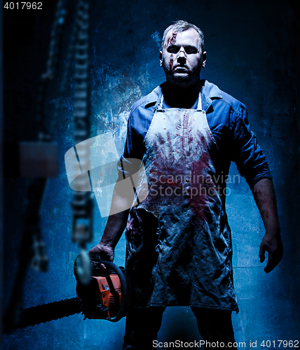 Image of Bloody Halloween theme: crazy killer as butcher with electric saw