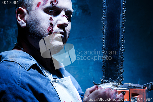 Image of Bloody Halloween theme: crazy killer as butcher with electric saw