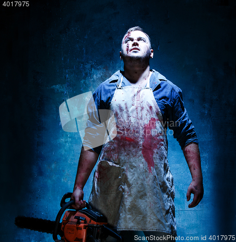 Image of Bloody Halloween theme: crazy killer as butcher with electric saw