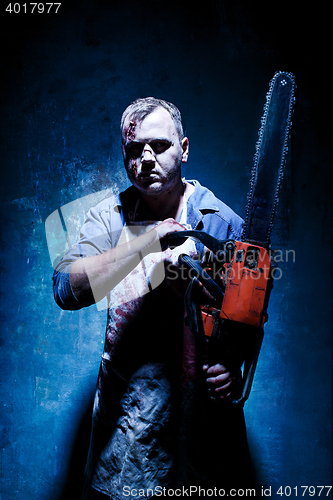 Image of Bloody Halloween theme: crazy killer as butcher with electric saw