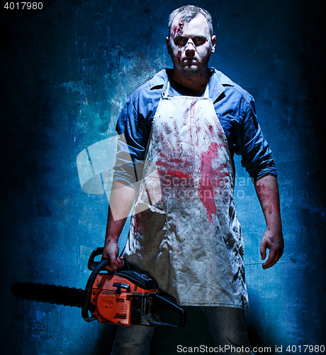 Image of Bloody Halloween theme: crazy killer as butcher with electric saw