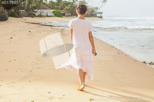 Image of Woman walking on the beach sand