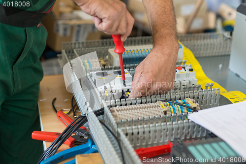 Image of Electrician assembling industrial electric cabinet.