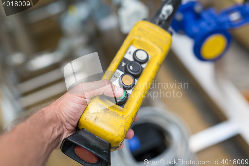 Image of Industrial worker pushing on button of machinery controler.
