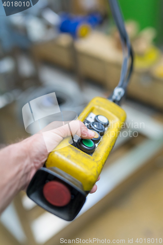 Image of Industrial worker pushing on button of machinery controler.
