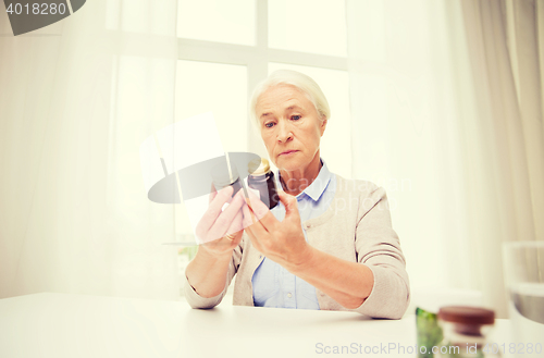 Image of senior woman with medicine jars at home