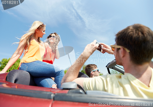 Image of friends driving in car and photographing
