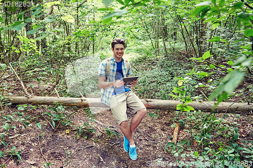 Image of happy man with backpack and tablet pc in woods